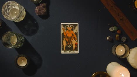 Overhead-Shot-Of-Person-Giving-Tarot-Card-Reading-Laying-Down-The-Devil-Card-On-Table